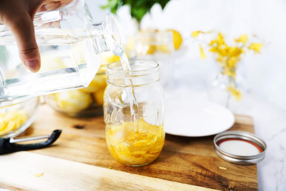 Peeled lemon pieces in a mason jar with vodka.