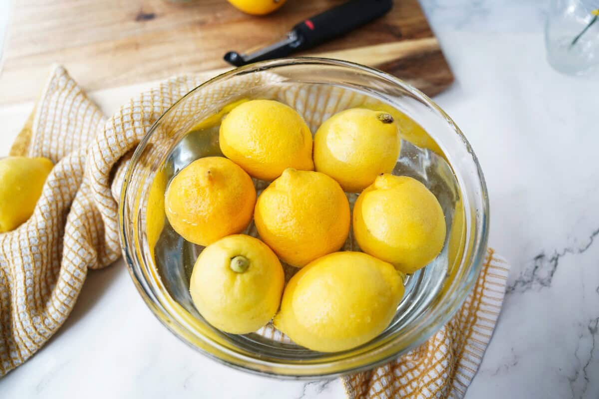 Lemons rinsing in a bowl of water.