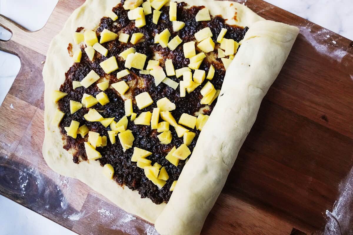 Spread the filling and diced apple and roll the dough.
