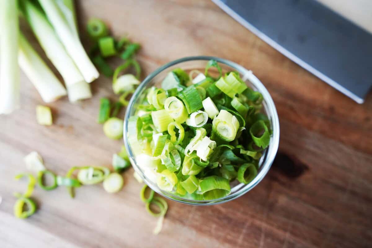 overhead view of diced green onions in glass bowl