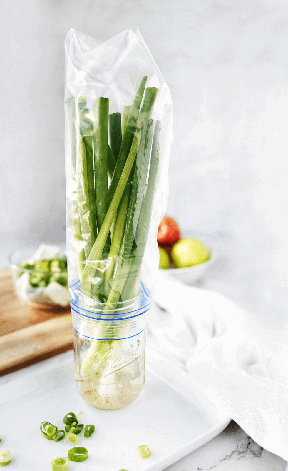 Green onions in a mason jar wrapped with a plastic bag