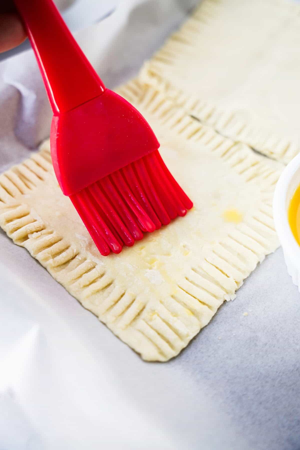 pastry brush brushing on melted butter to puff pastry