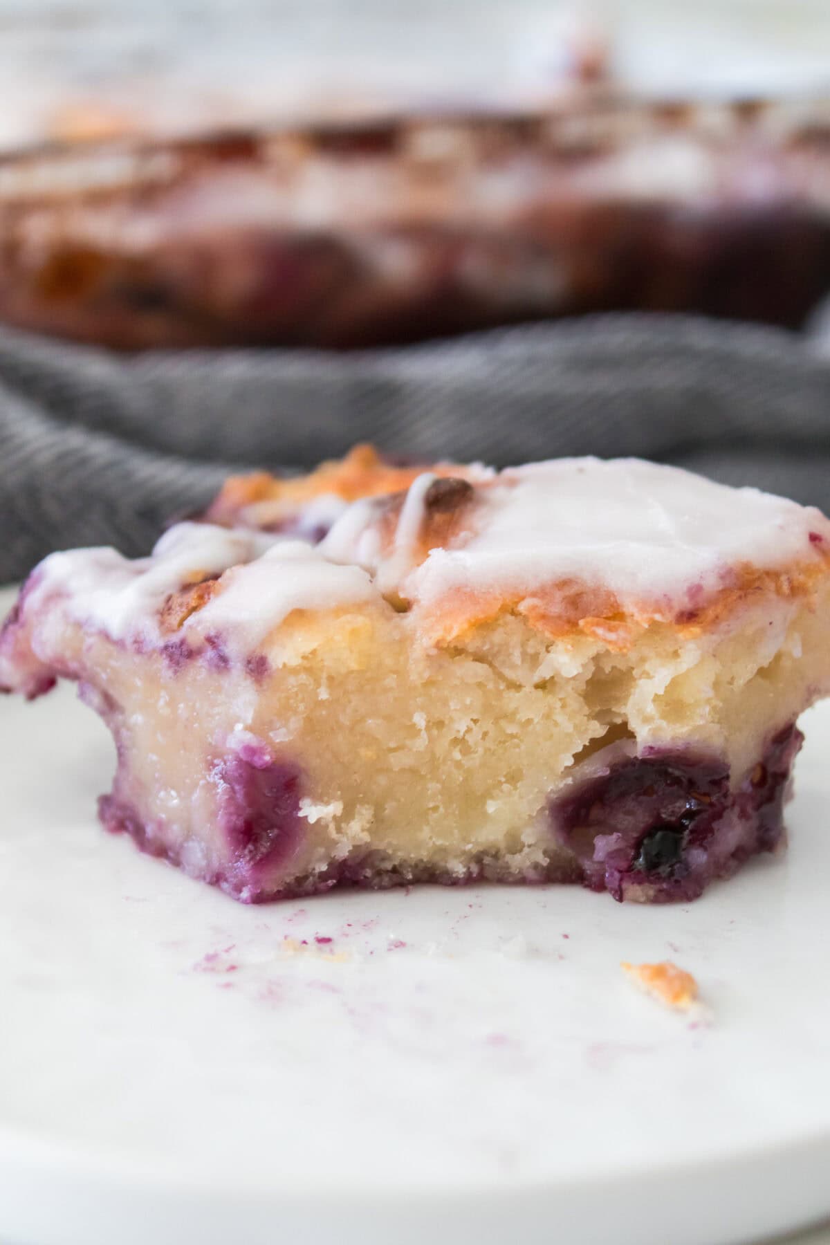 head on vertical shot of bite taken out of blueberry butter swim biscuit on white plate