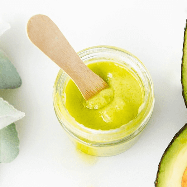 Homemade Avocado Face & Body Cream in container with flower and avocados