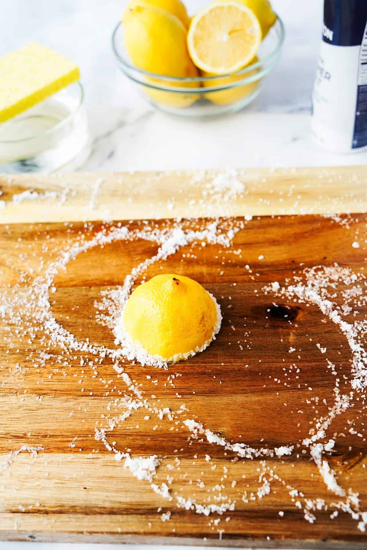 lemon cut in half, face down on wood cutting board with kosher salt