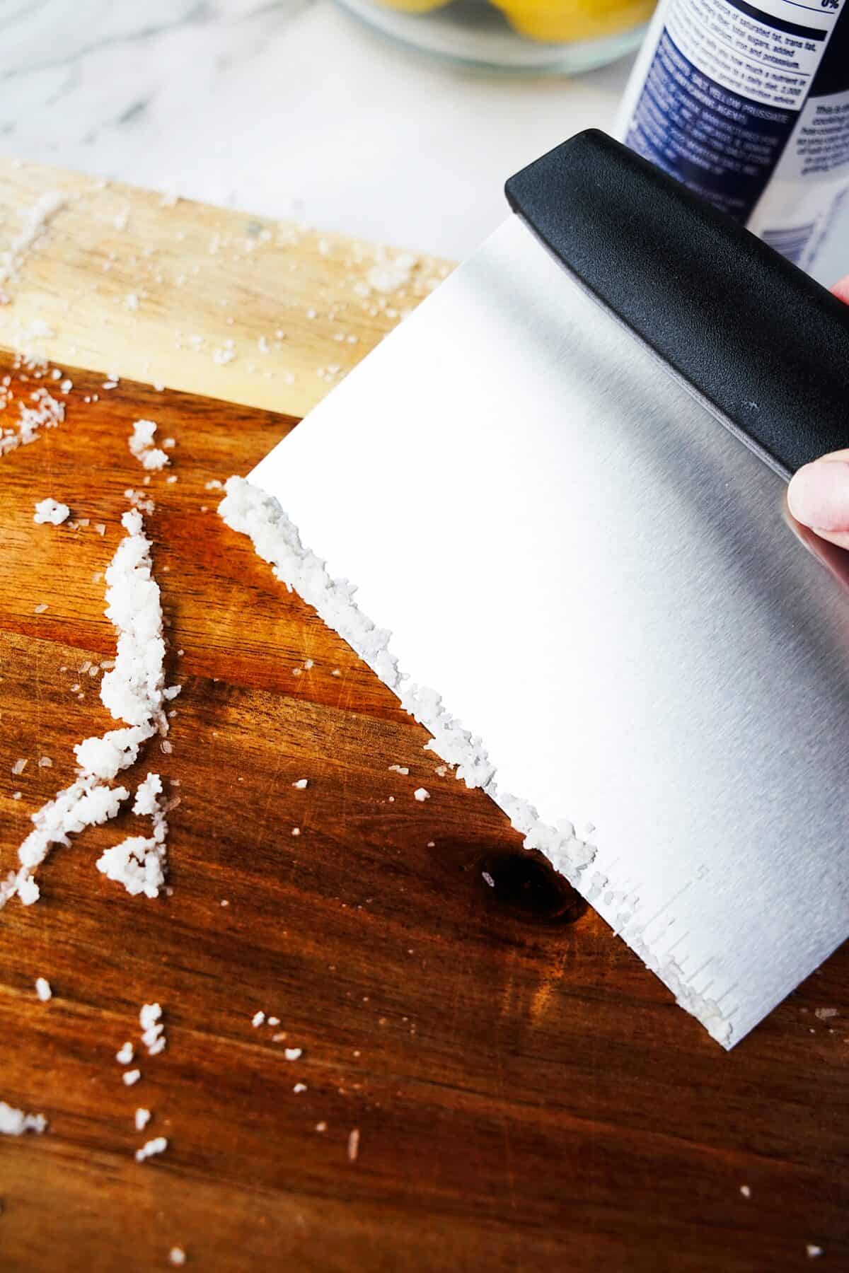 hand scraping wood cutting board to clean