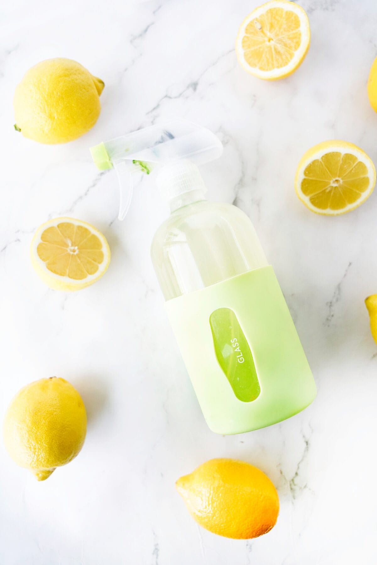 glass cleaner with lemons in spray bottle with halved lemons scattered on counter