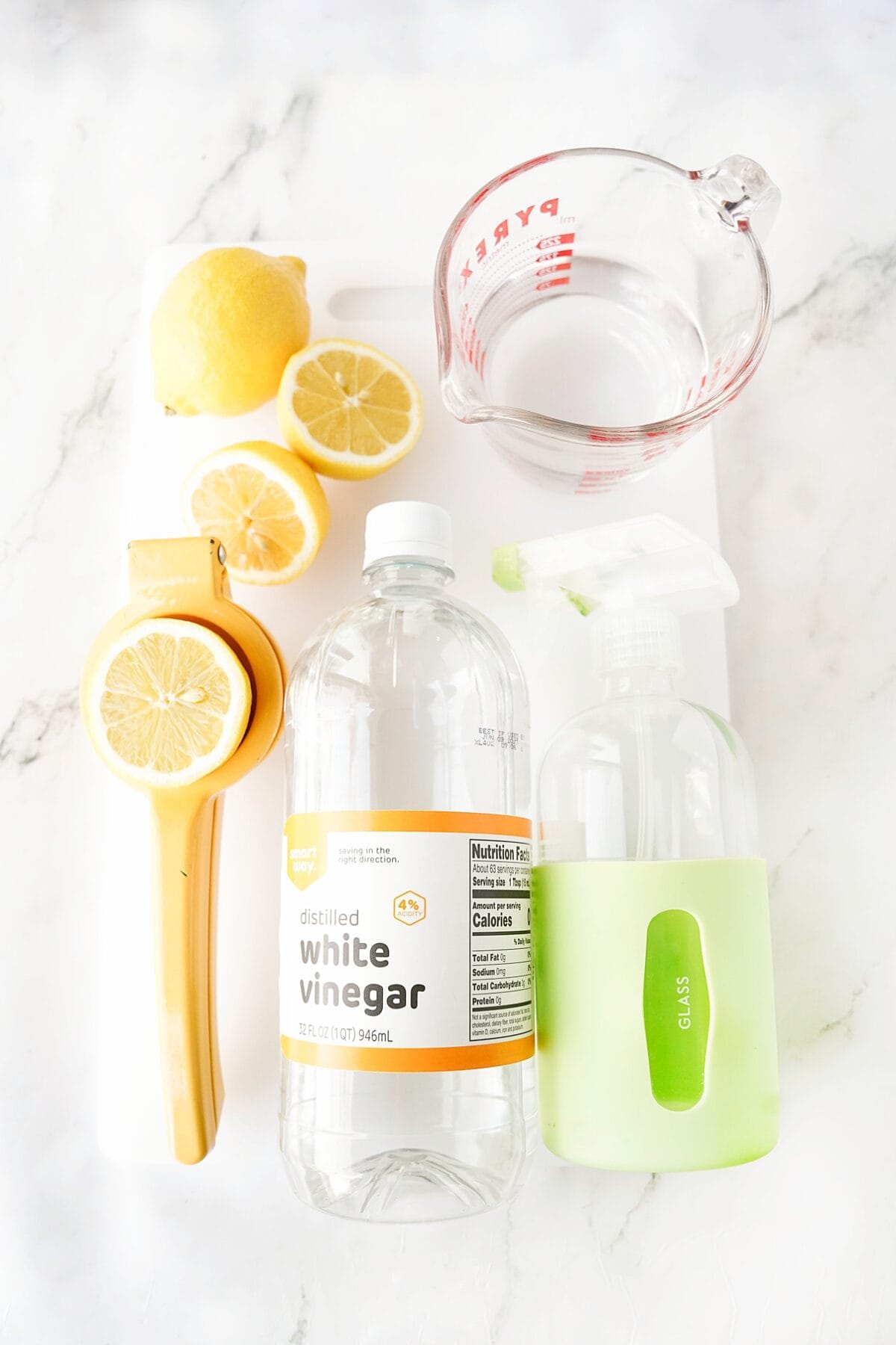 lemons, white vinegar, water and spray bottle for glass on cutting board