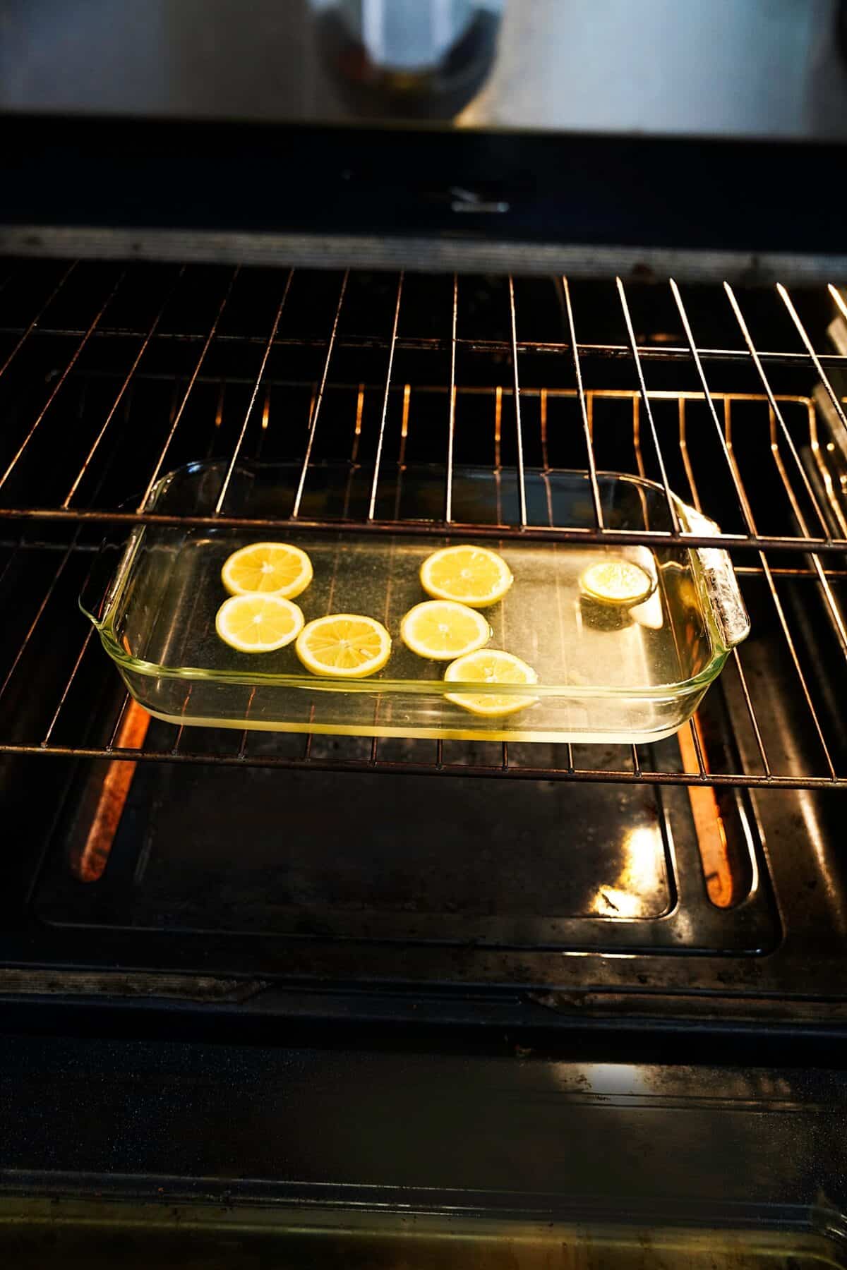 glass baking dish with water and slices of lemon in oven to clean