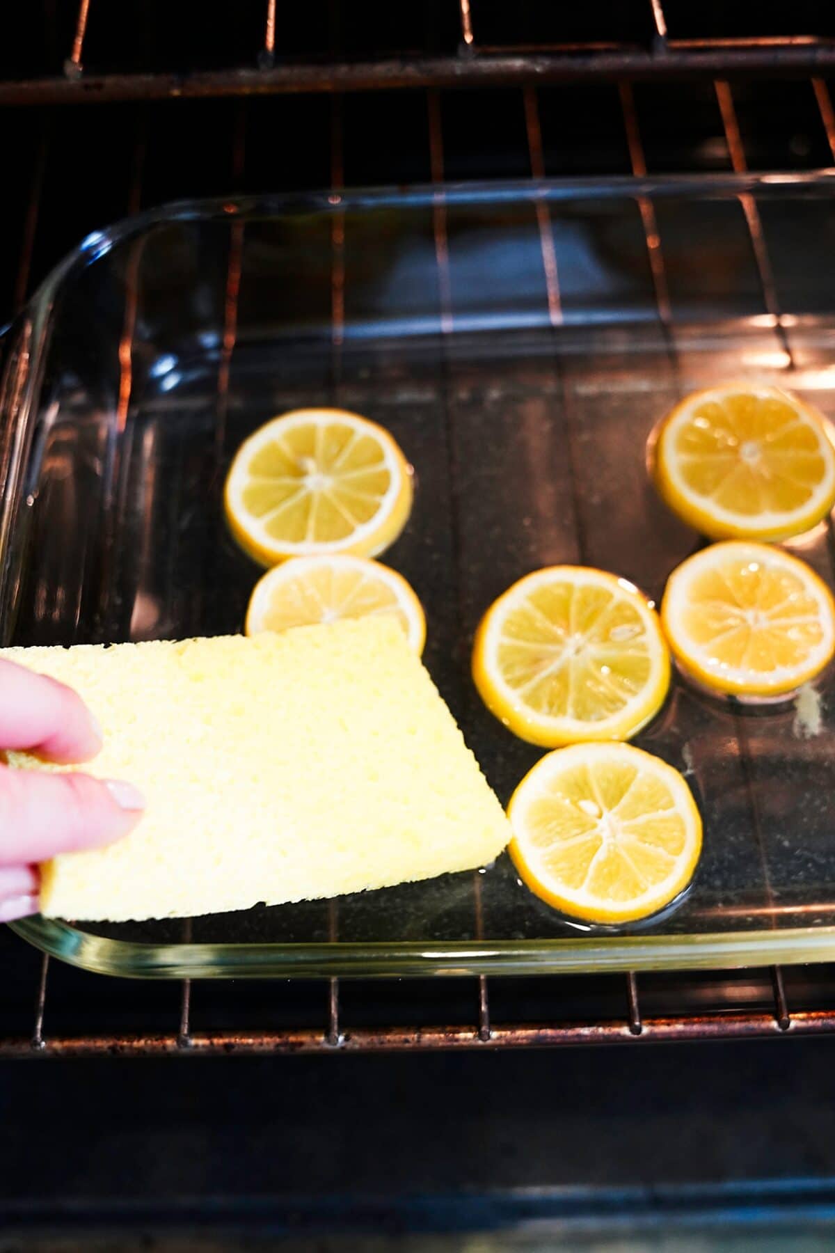 sponge being dipped in water to clean oven