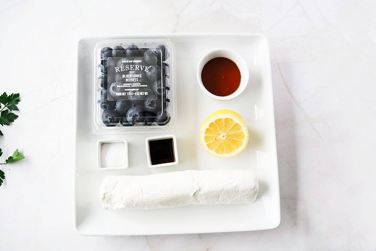 overhead shot of ingredients for blueberry goat cheese log on white serving platter
