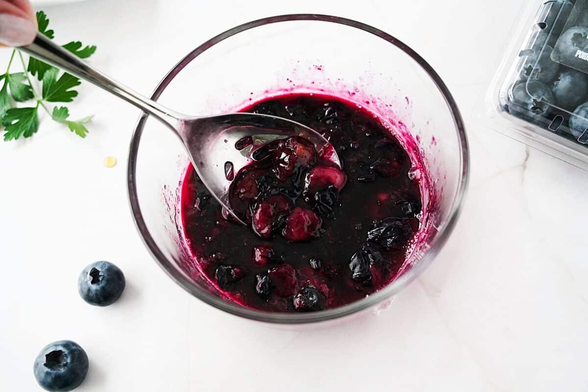 blueberry sauce in glass bowl with white spoon