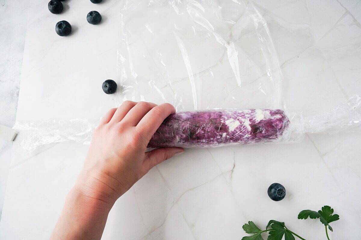 blueberry goat cheese log being wrapped in plastic wrap
