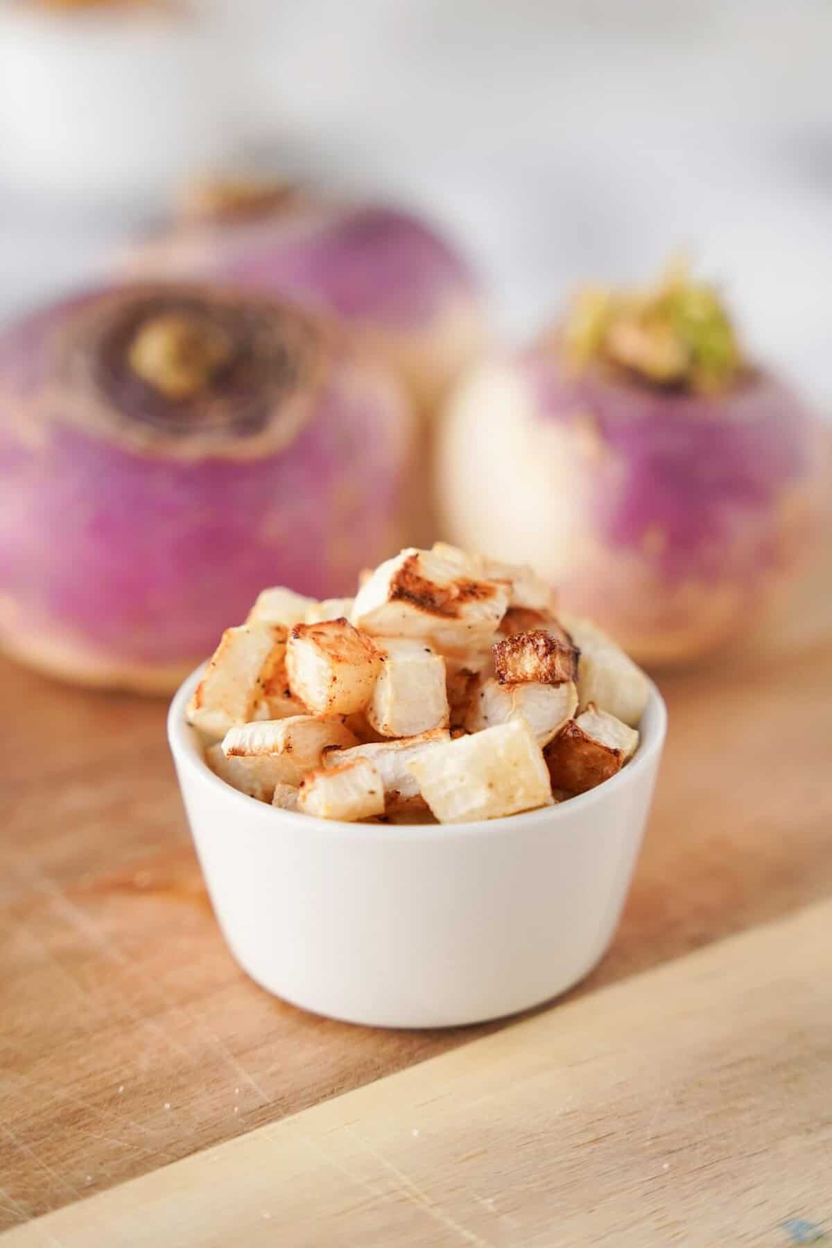 Vertical image of roasted turnips in white bowl