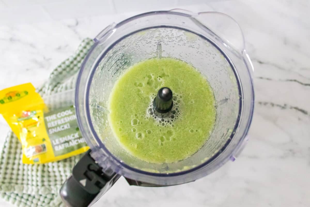 overhead shot of food processor with cucumbers, sprite and lemon juice that has been blended