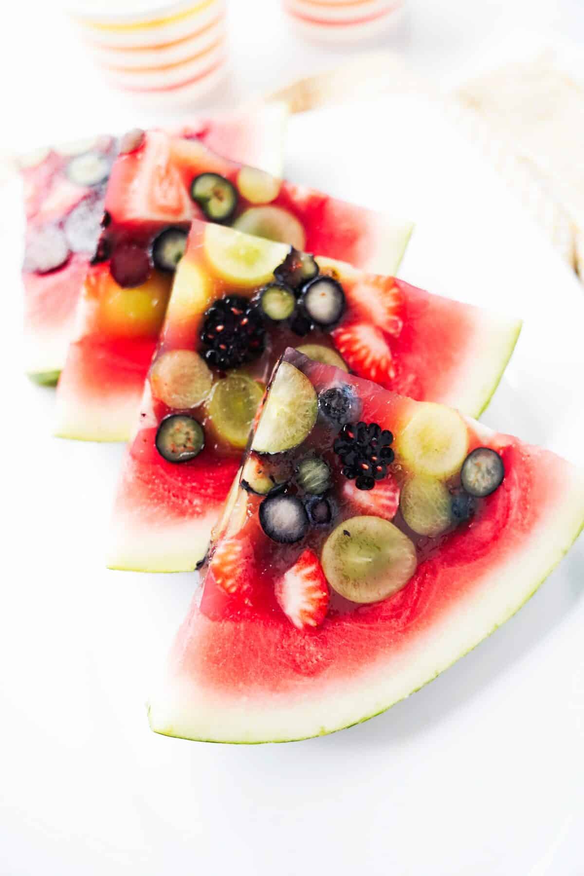 watermelon slices with jello and grapes, strawberries, blueberries, blackberries on white serving platter