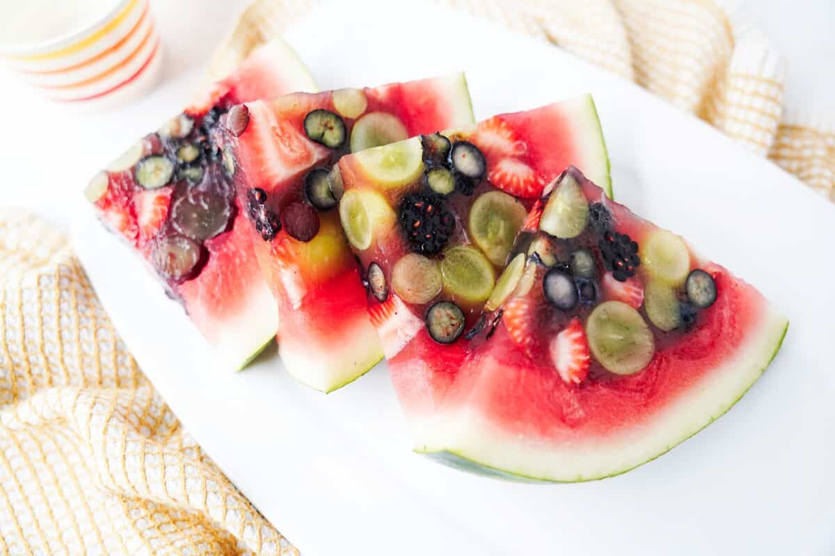close up shot of watermelon slices that are loaded with fresh fruit being held together with jello