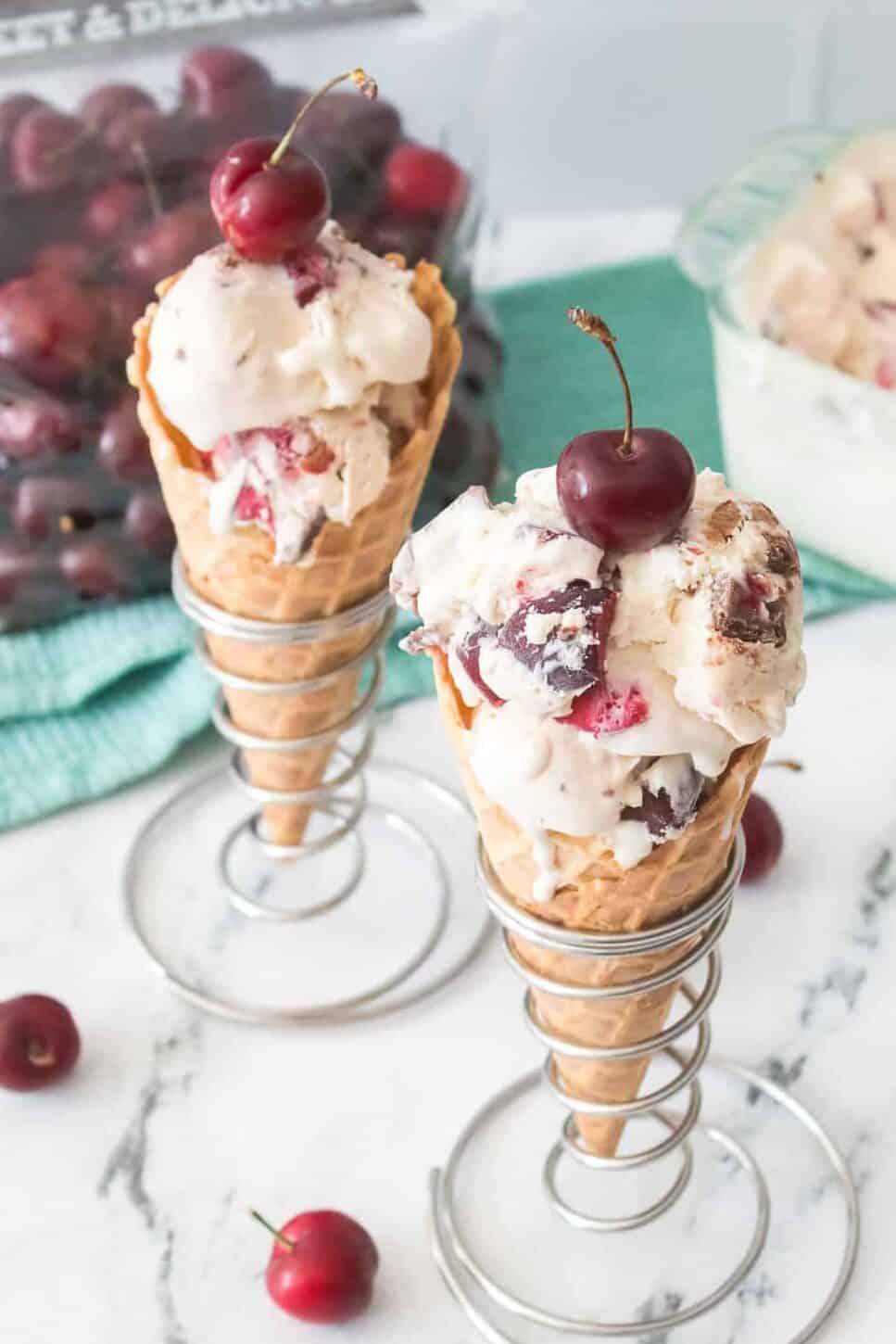 overhead shot of cherry garcia ice cream served in a waffle cone and topped with a fresh cherry