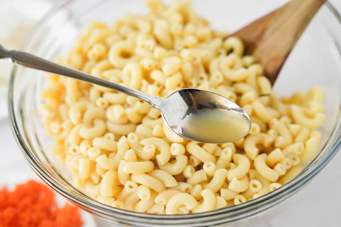 spoon of vinegar over pasta in a glass bowl
