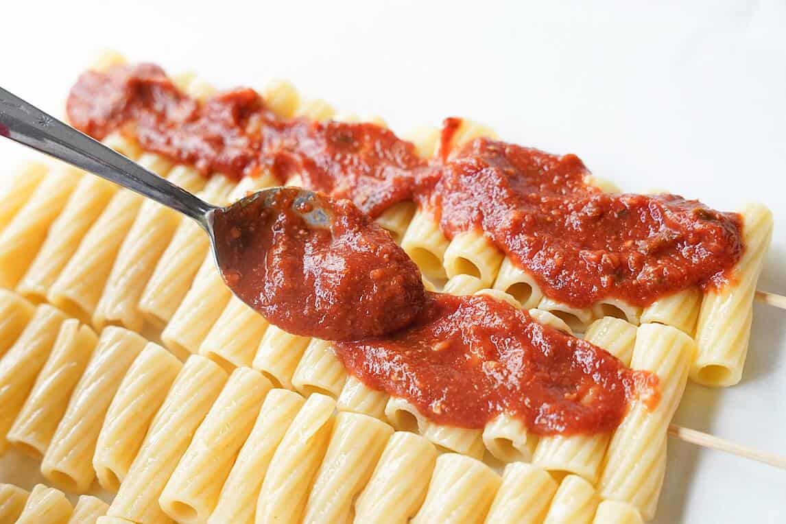 Layering sauce on the pasta kabobs