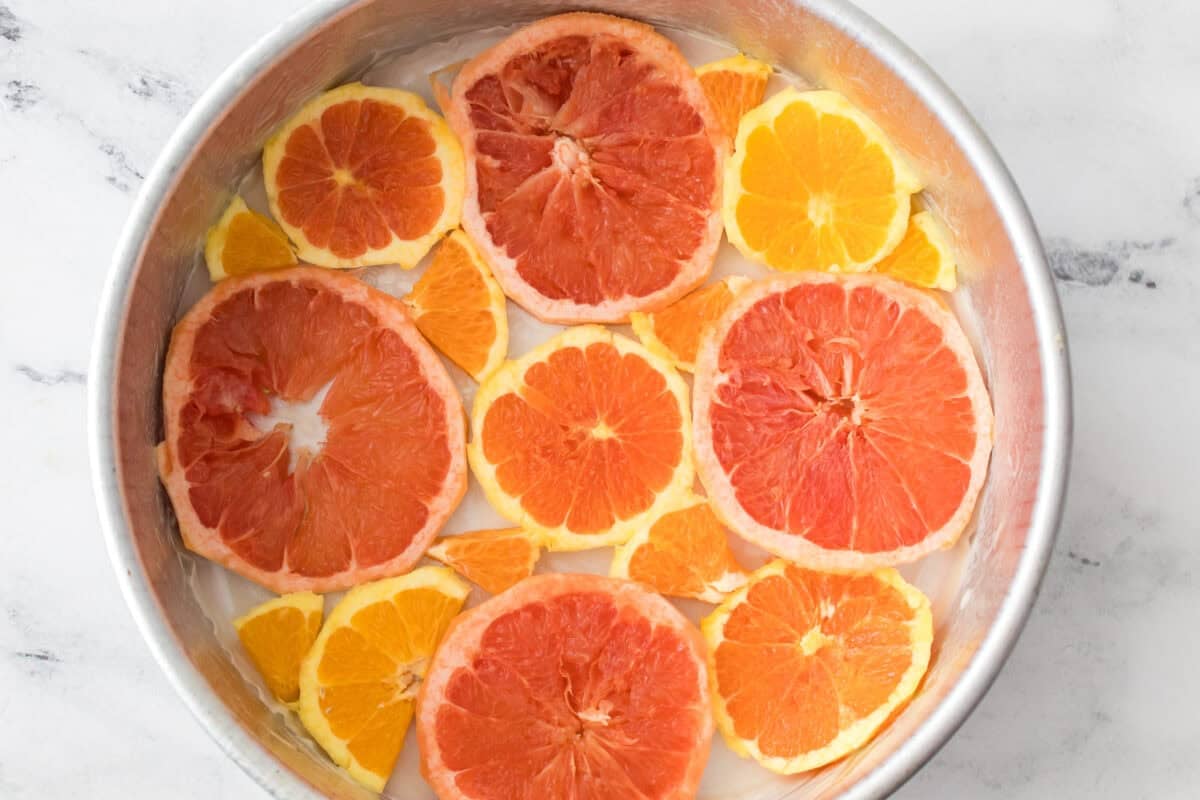 slices of oranges, cara caras oranges and grapefruit in bottom of cake pan with pieces filling in the gaps