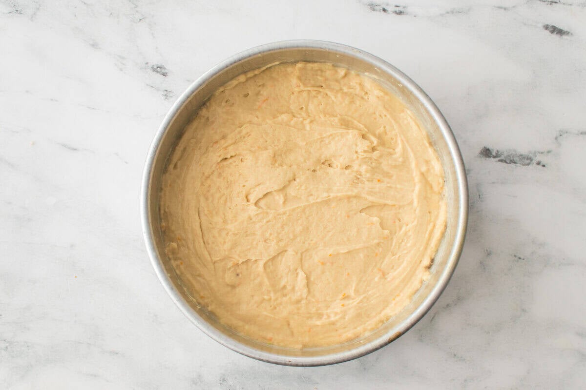 cake batter over the top of citrus slices and pieces in cake pan before baking