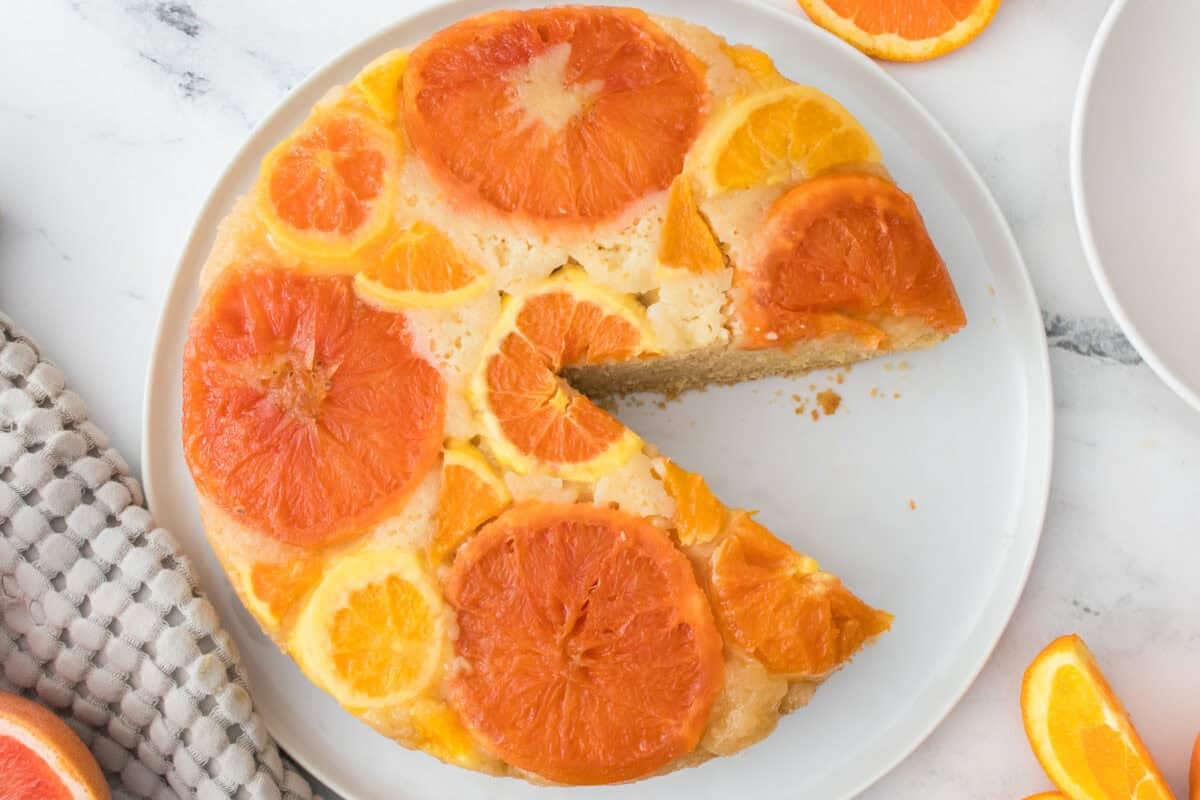 upside down citrus cake with piece taken out served on a white plate