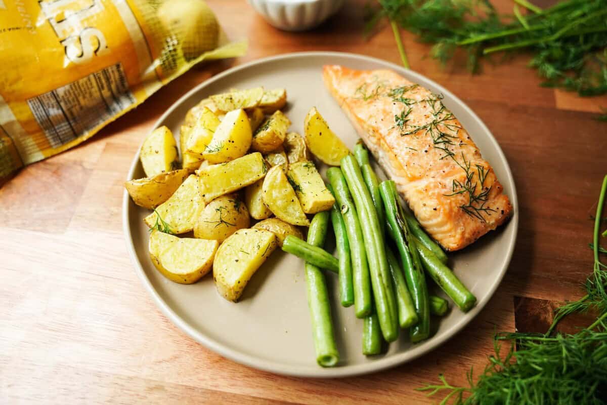 Roasted potatoes on a plate with fish and green beans