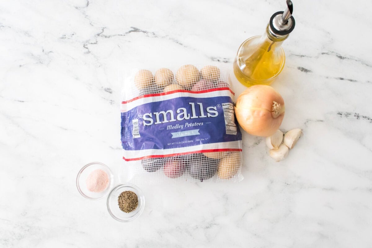 ingredients to make foiled potatoes: wada farms smalls medley potatoes, bottle of olive oil, onion, garlic cloves, salt and pepper