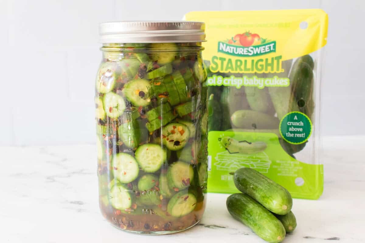 wide mouth mason jar with naturesweet starlight baby cucumbers in background with quick pickled cucumbers