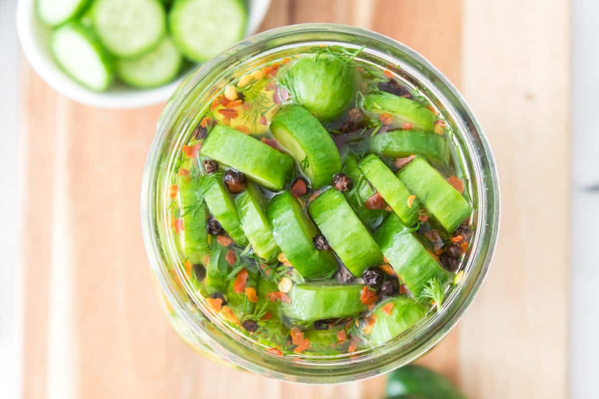 overhead shot of quick pickled cucumbers in mason jar sitting on cutting board after marinating for an hour