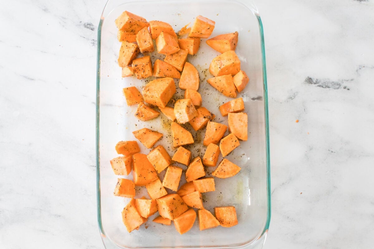 sweet potatoes in glass baking dish with olive oil, garlic powder, salt and pepper previous to baking