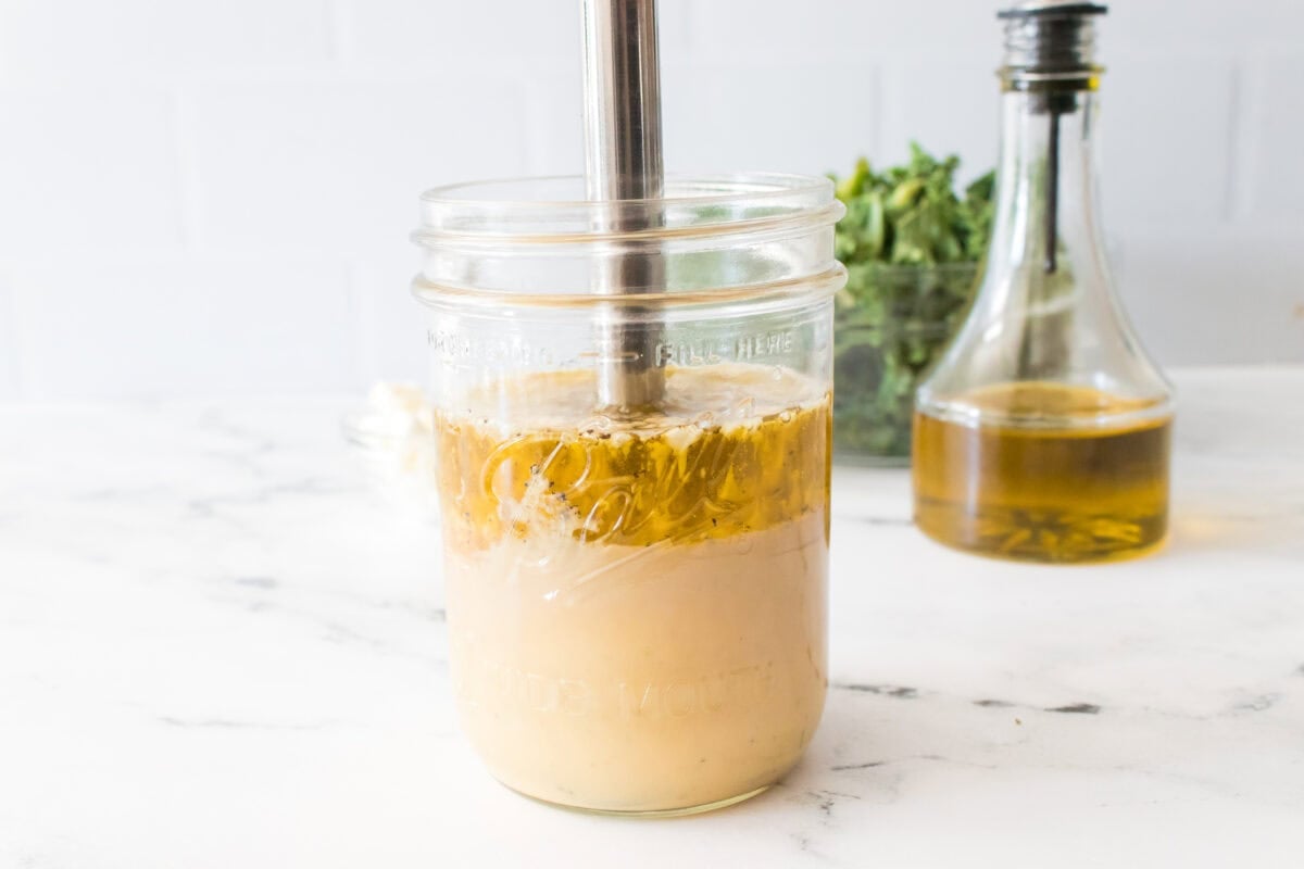 head on shot of a wide mouth ball mason jar with immersion blender making a tahini maple dressing