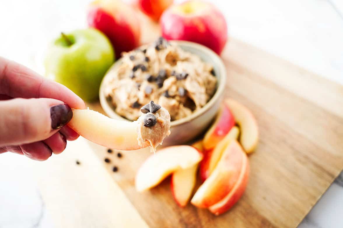 hand holding apple slice with apple toffee dip
