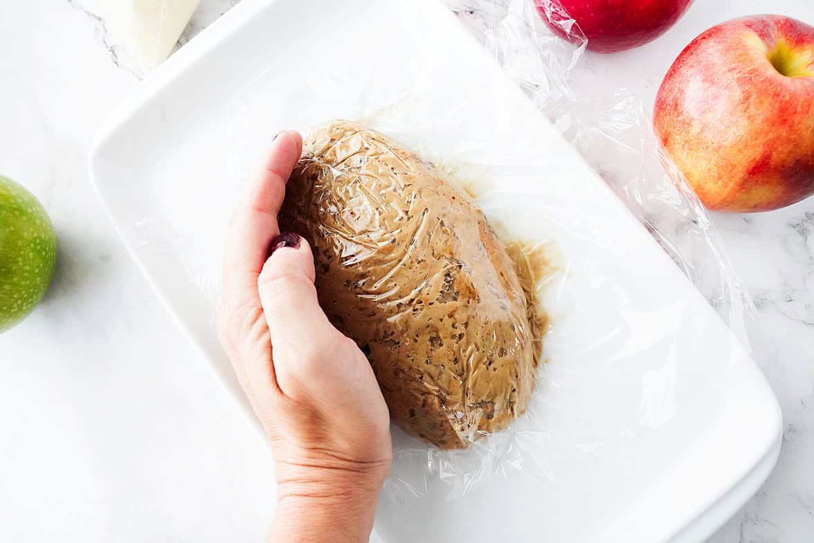 overhead shot of apple toffee dip on white plate with saran wrap over to form a football shape