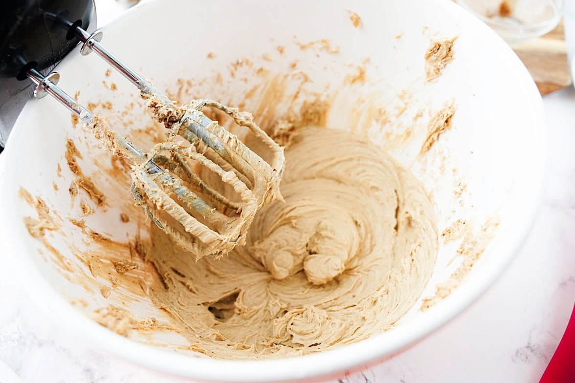 cream cheese, brown sugar, sugar, vanilla and salt being creamed together in white bowl with hand mixer