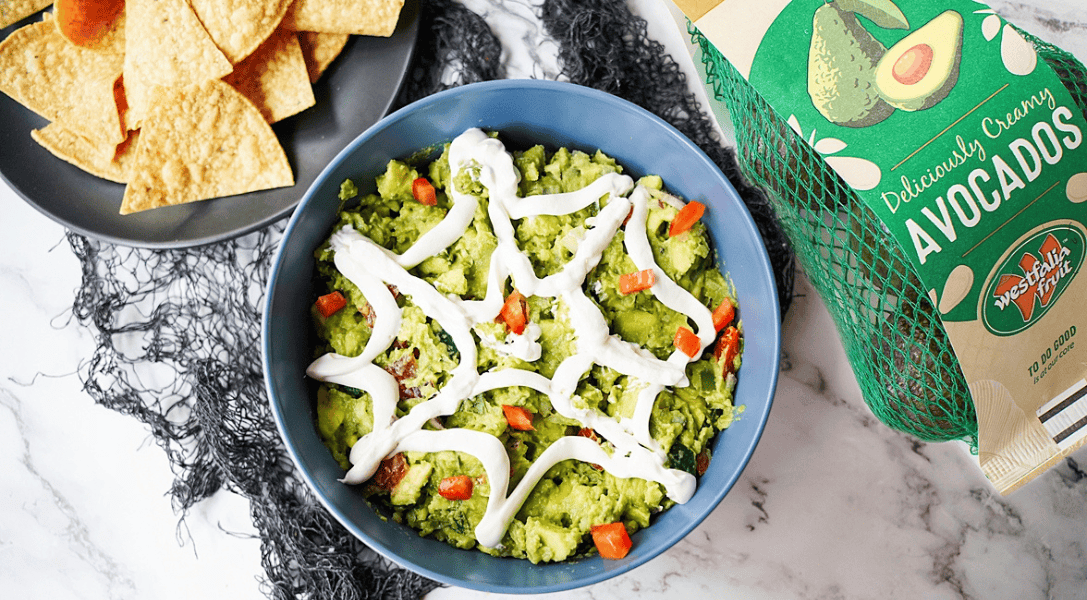piderweb Guacamole in bowl with a bag of Westfalia Fruit avocados to the right