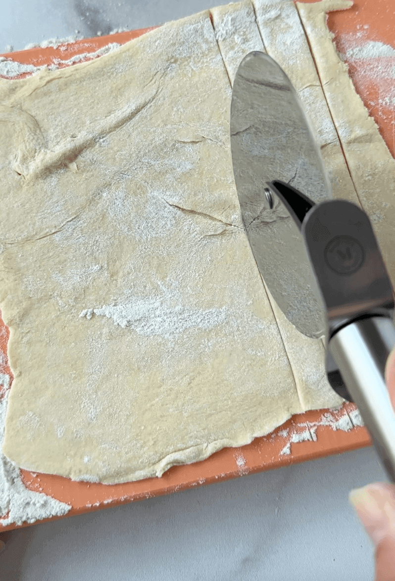 Cutting the dough into strips with a pizza cutter