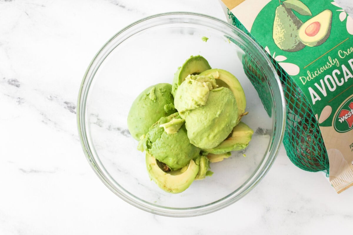 overhead shot of 4 avocados in glass bowl with bag of westfalia fruit avocados
