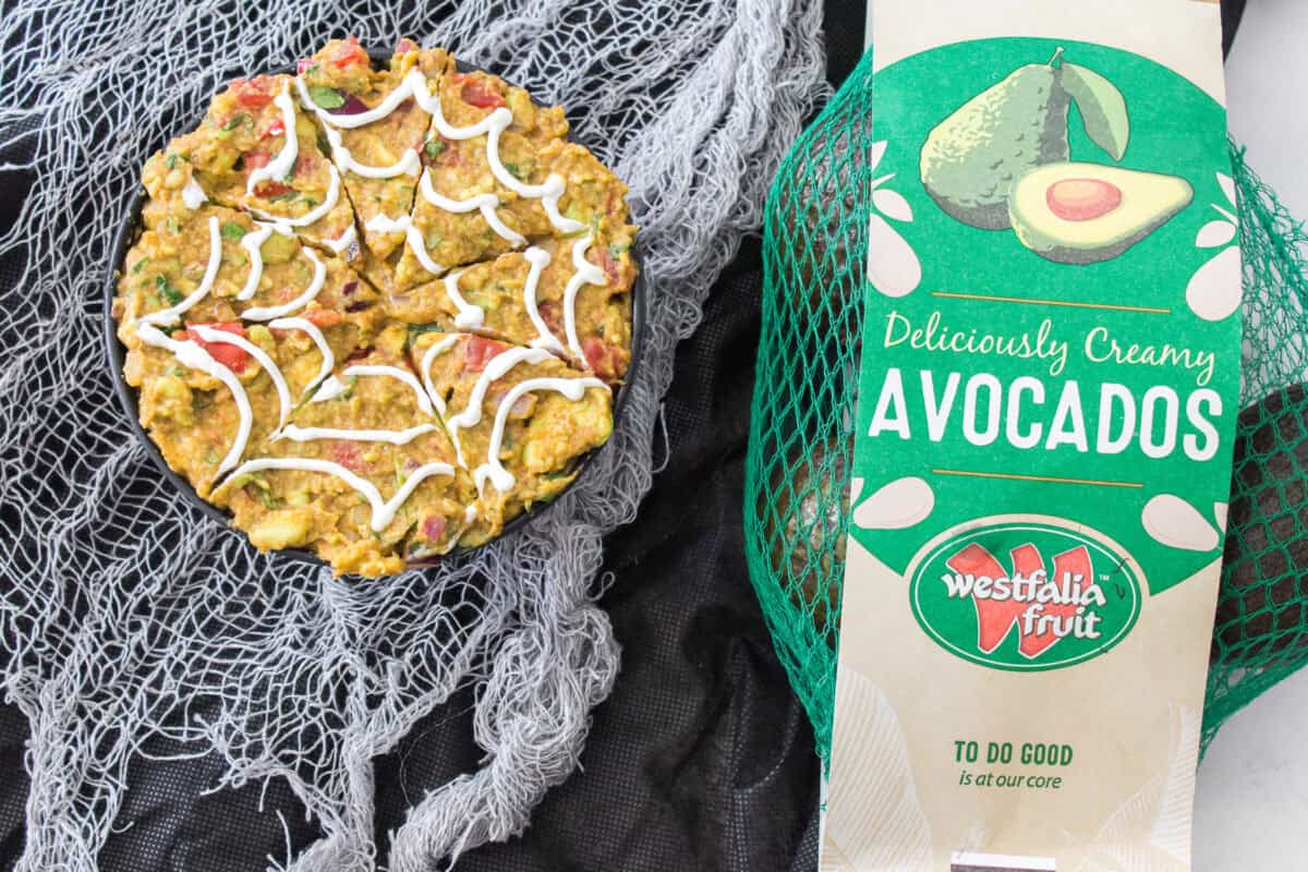 overhead shot of spiderweb gauacamole with bag of westfalia fruit avocados