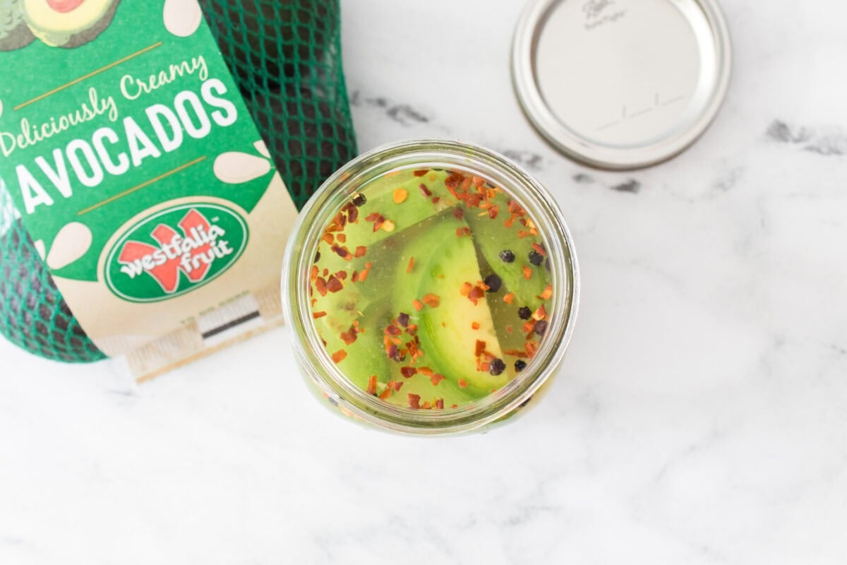 overhead shot of bag of westfalia fruit avocados and big mouth mason jar with pickled avocados