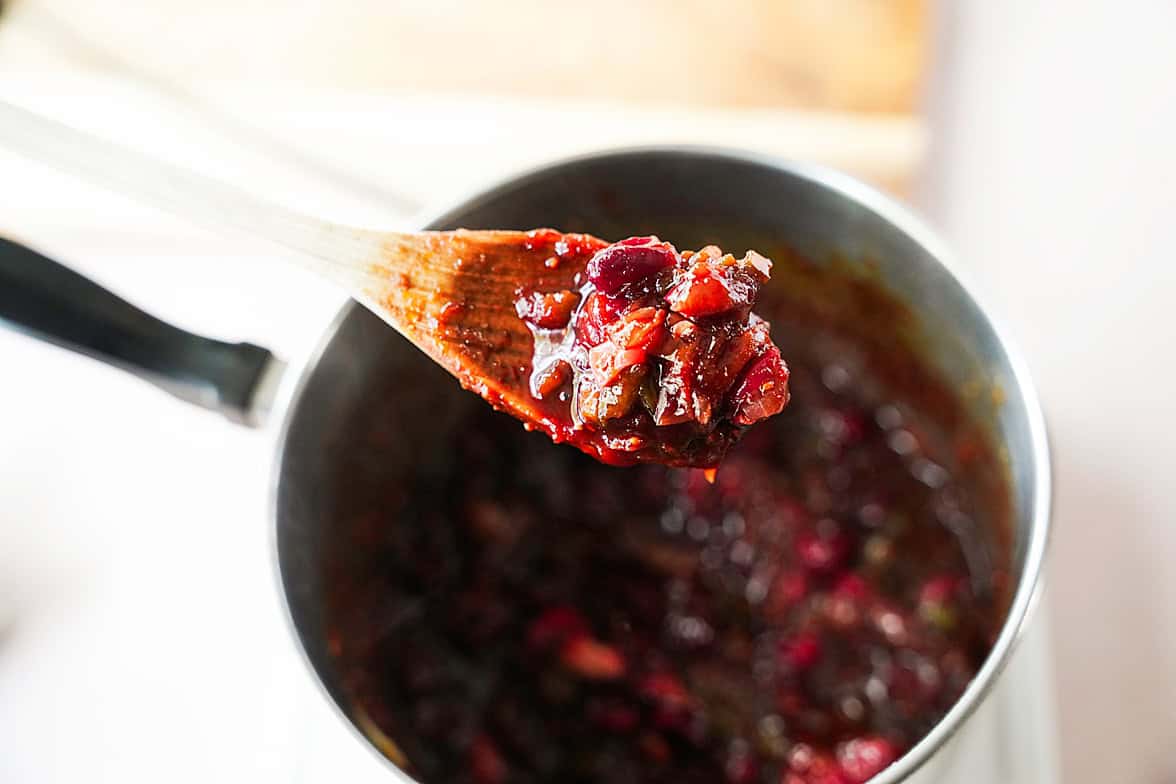 cranberry mixture on wooden spoon to show the thickness