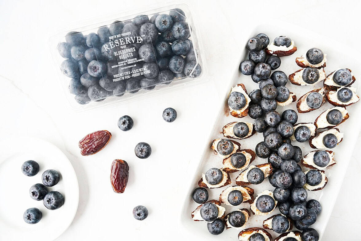 overhead view of a plate full of mascarpone dates with blueberries and a container fo the North Bay Reserve blueberries 