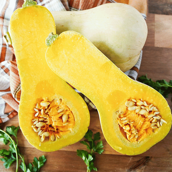 butternut squash cut in half on cutting board with flesh side up