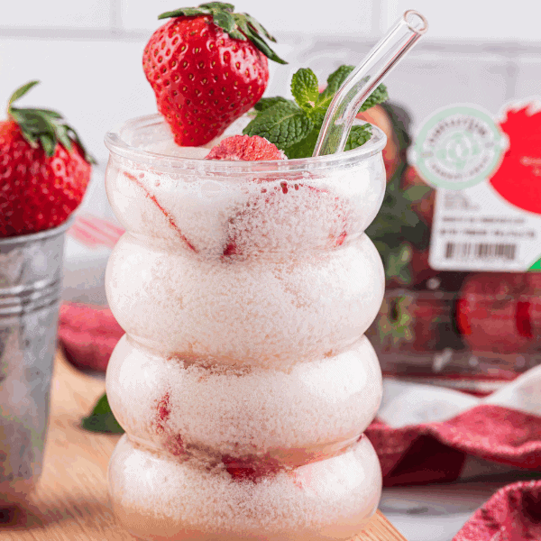 Strawberry Dirty Soda in glass surrounded by Naturipe strawberries