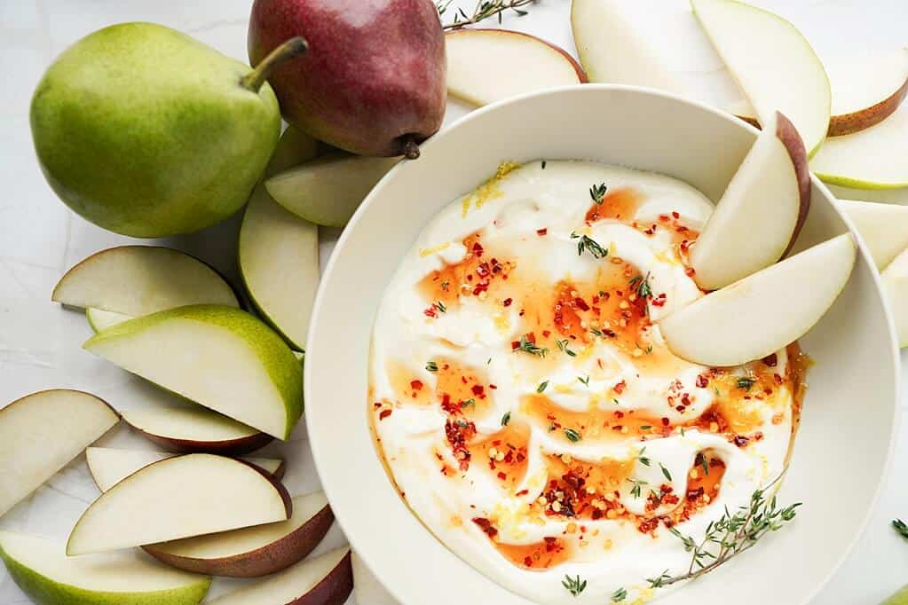 Hot Honey Whipped Ricotta Dip with slices and whole pears surrounding the bowl