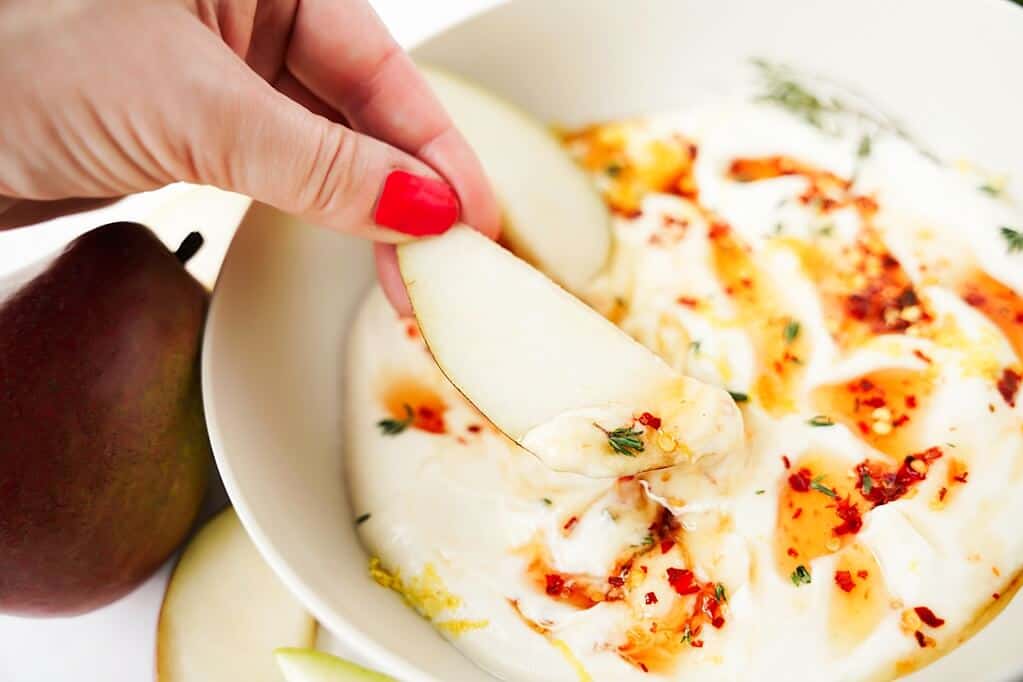 Dipping pear slice into Hot Honey Whipped Ricotta Dip