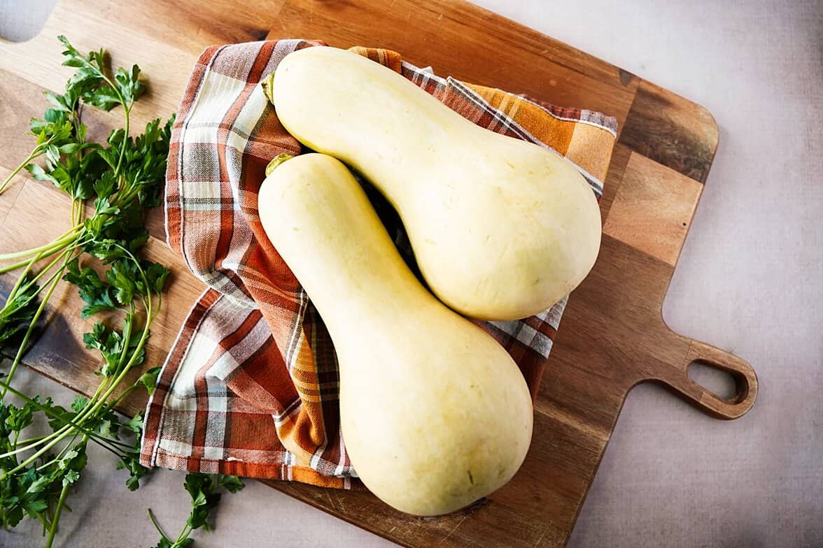 overhead view of 2 butternut sqush on a cutting board with a napkin