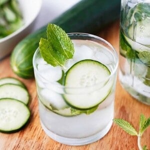 glass of cucumber water with mason jar behind