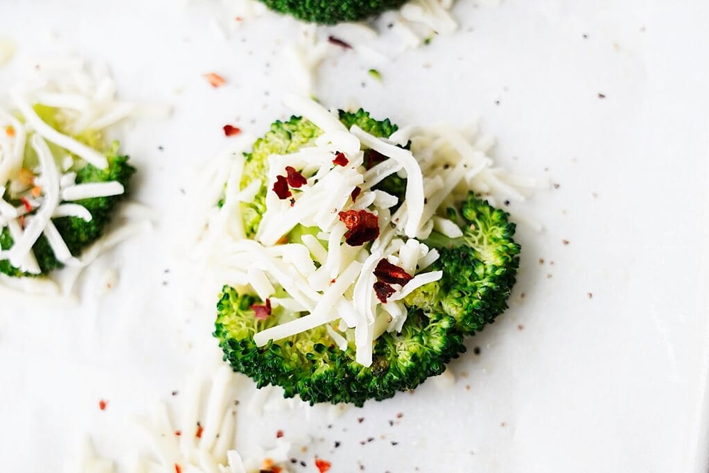 shredded cheese and seasoning on top of smashed broccoli bite